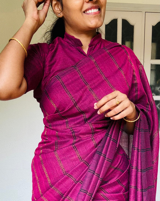 Woman wearing a wine  purple Khadhi  saree with black patterns indoors.
