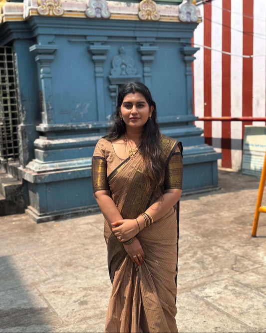 Woman in a traditional saree standing in front of a temple structure.