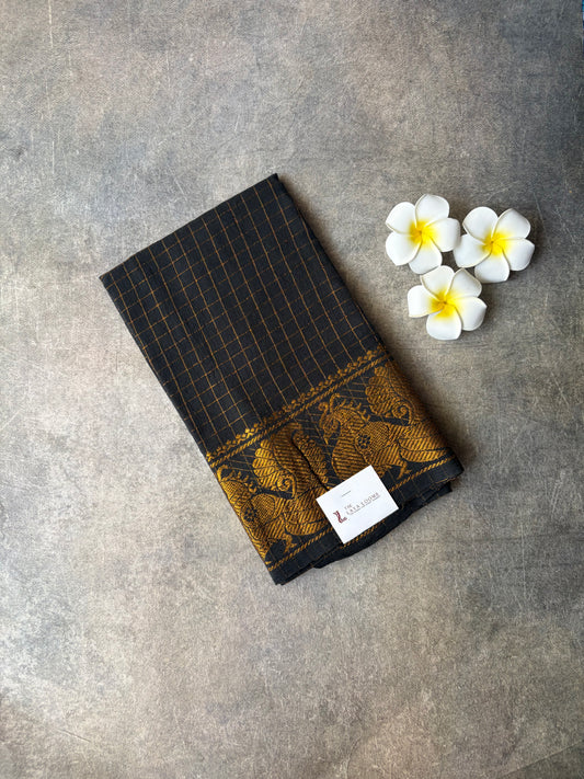 Black and gold patterned  Sungudi Blouse Material with a label on a gray surface, accompanied by white flowers.