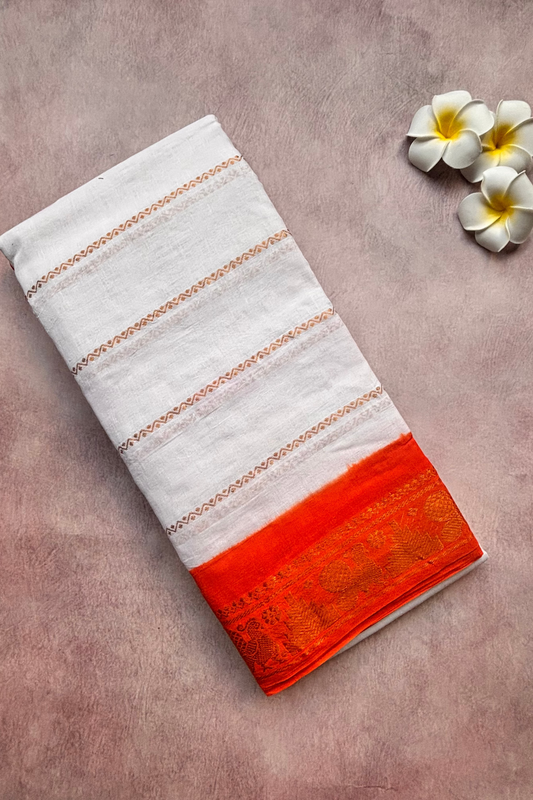 Folded white Sungadi  saree with orange hem on a textured surface with flowers.